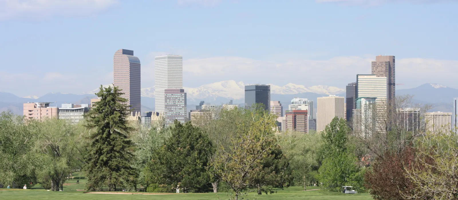 Denver skyline with the Front Range behind it, seen from City Park