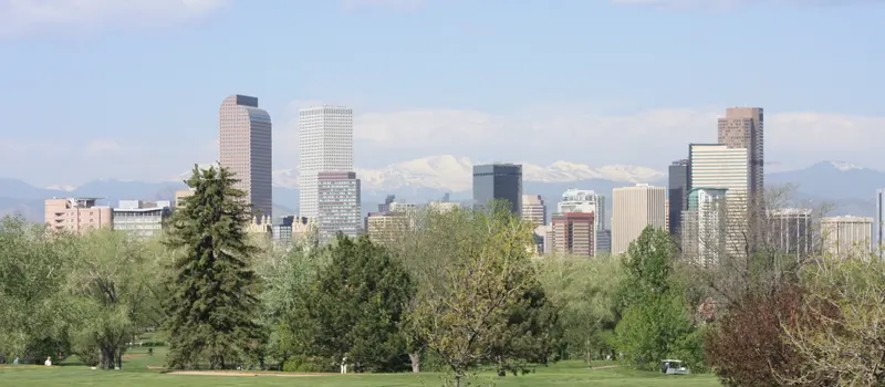 Denver skyline with the Front Range behind it, seen from City Park